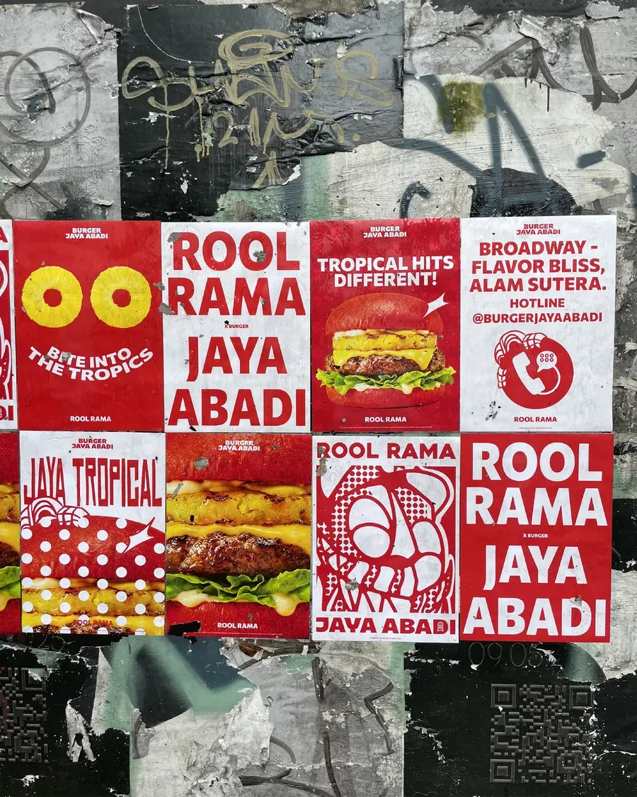 Dinding penuh poster kolaborasi Rool Rama x Burger Jaya Abadi