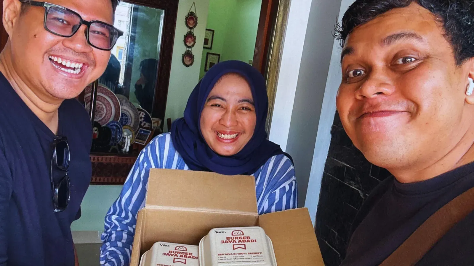 Pelanggan tersenyum menerima box Burger Jaya Abadi