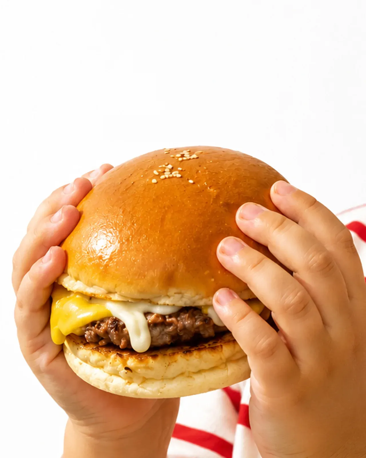 Tangan anak memegang cheese burger Burger Jaya Abadi dengan cloud bun